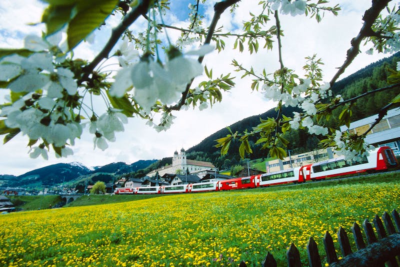 Glacier-Express vor dem Kloster Disentis im Fruehling - ©Tibert Keller, Rhaetische Bahn
