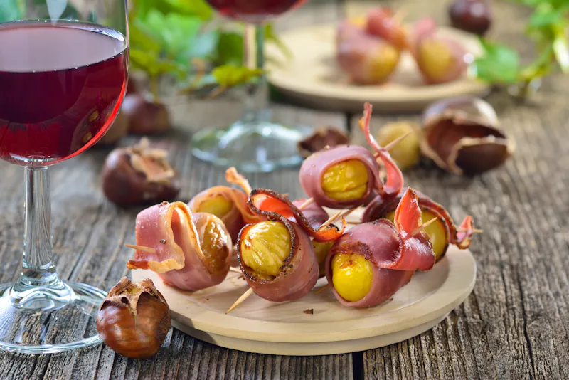 Gebackene Maroni im Südtiroler Speck als Fingerfood zum Törggelen mit regionalem Wein gereicht  - &copy;kab-vision - stock.adobe.com