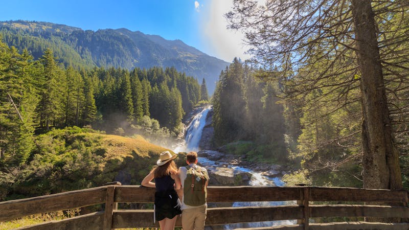Junges Paar betrachtet die Krimmler Wasserfälle, die höchsten Wasserfälle Europas - ©©mmuenzl - stock.adobe.com