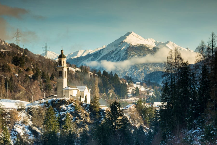 Tiefencastel in den Schweizer Alpen - Kirche und Bergpanorama im Winter – © ©makasana photo - stock.adobe.com