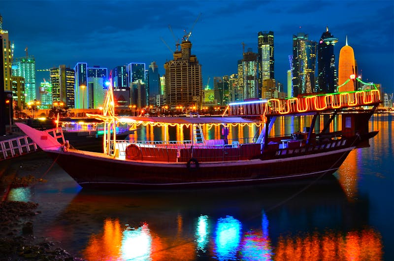Katar – Doha Skyline mit beleuchtetem Dhau-Boot am Abend - ©vikas_72 - stock.adobe.com