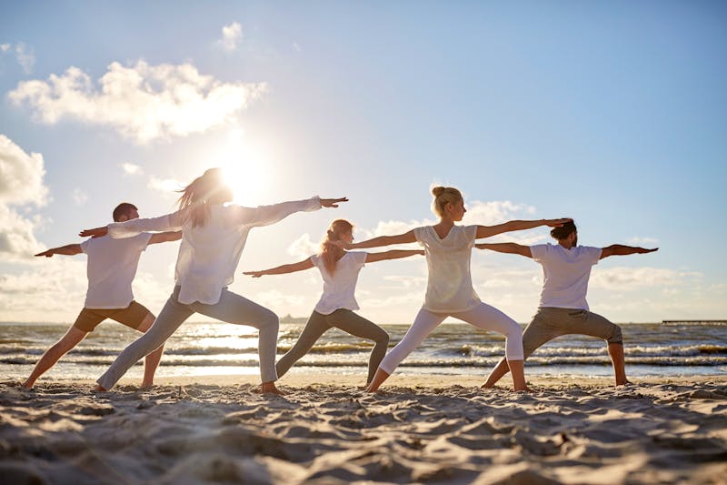 Wellness-Gruppe macht Yoga am Strand - ©lev dolgachov - stock.adobe.com