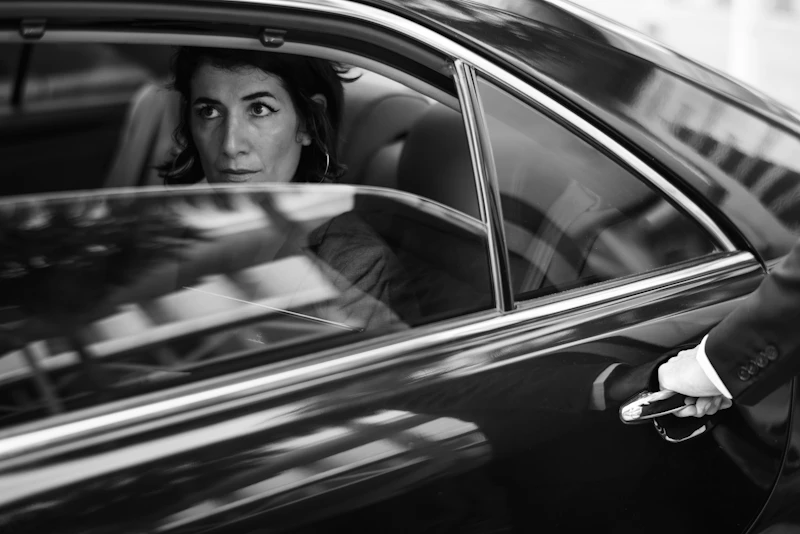 Chauffeur öffnet einer Kundin die Tür einer Limousine