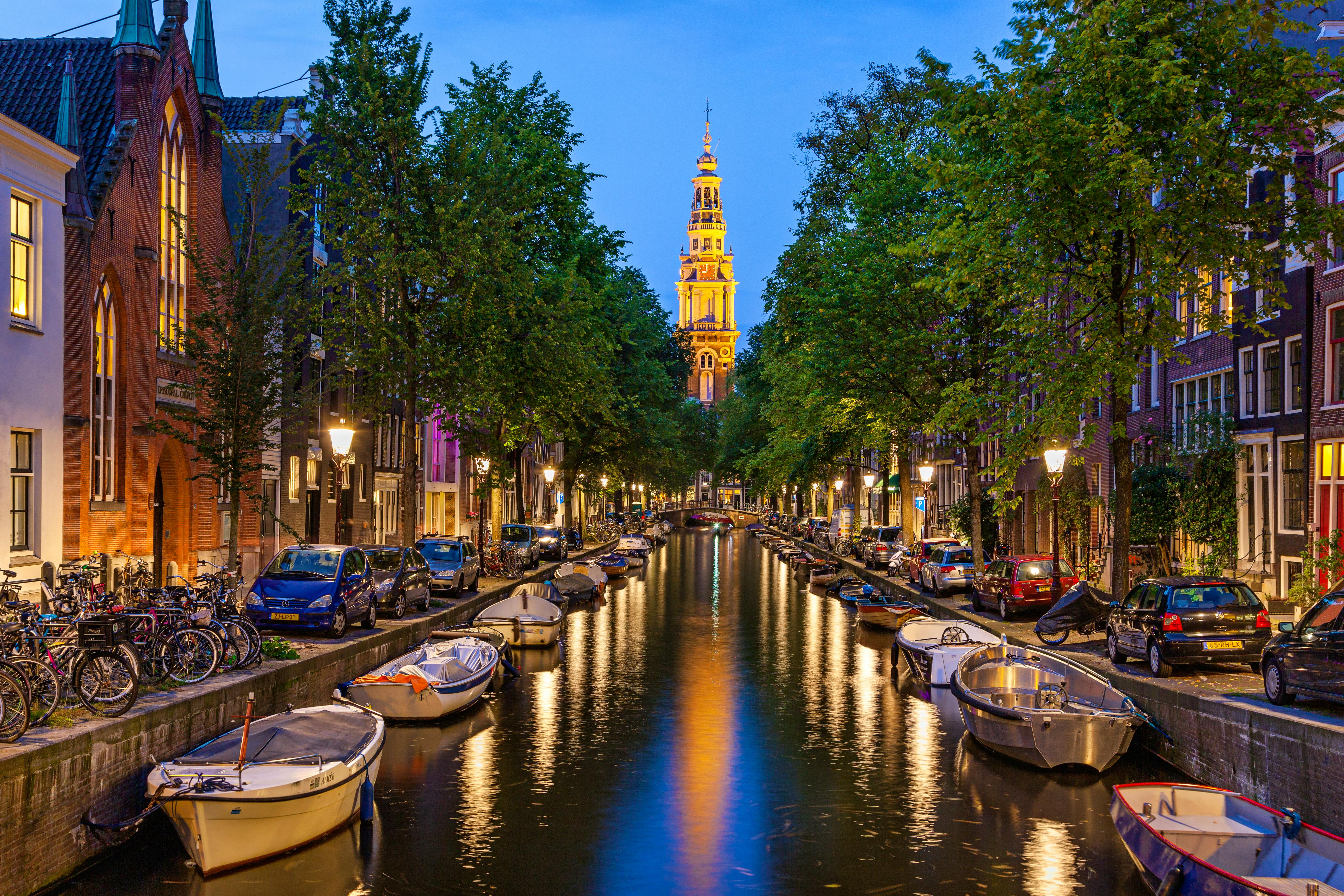Traditional view of canals in Amsterdam where boats  bicycles and cars on same street  &copy; SakhanPhotography - Fotolia