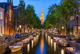 Traditional view of canals in Amsterdam where boats  bicycles and cars on same street  – © SakhanPhotography - Fotolia