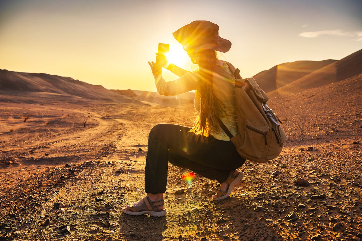 Sonnenuntergang in der Wüste Gobi - Touristin fotografiert das Naturschauspiel – © cppzone - stock.adobe.com