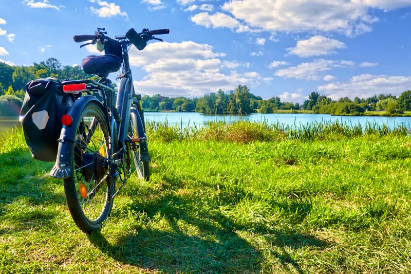 Packed touring bike on a meadow in front of a pond during a bike tour through Germany - ©Frank - stock.adobe.com