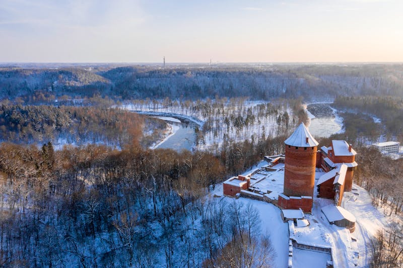 Burganlage Turaida bei Sigulda im Winter - Blick auf die Burg und den verschneiten Wald - ©Ingusk - Adobe Stock
