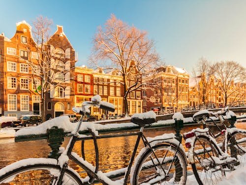 Amsterdam - mit Schnee bedeckte Fahrräder entlang einer Gracht im Winter &ndash; &copy; Martin Bergsma - stock.adobe.com