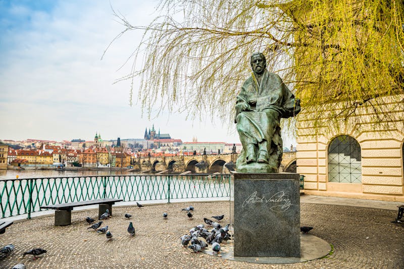 Prag - Bedrich-Smetana-Denkmal vor dem Smetana-Museum mit Blick auf Moldau und Karlsbrücke - &copy;marketanovakova - stock.adobe.com