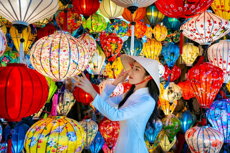 Hoi An - vietnamesische Frau in traditioneller Kleidung vor den berühmten Hoi-An-Laternen - ©tawatchai1990 - stock.adobe.com