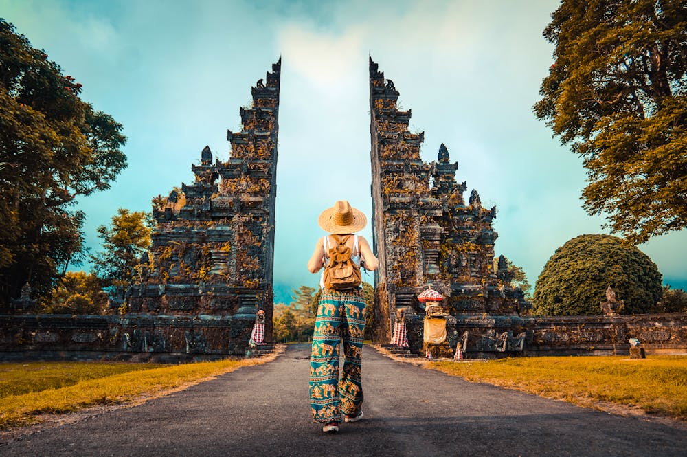 Bali - Frau mit Rucksack geht durch ein großes Eingangstor &ndash; &copy; Davide Angelini - stock.adobe.com