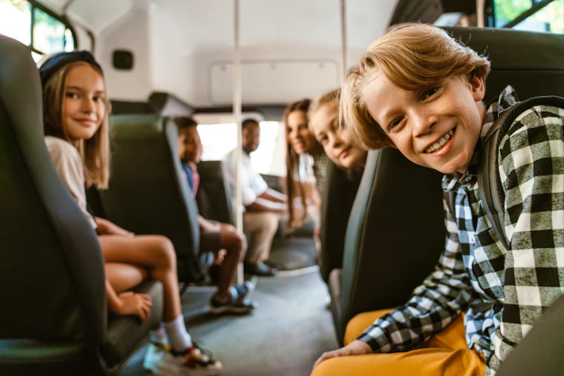 Schulkinder sitzen gemeinsam in einem Kleinbus